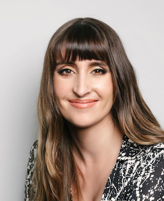 A woman in bangs smiles at the camera.