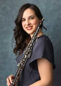 Emily Snyder holding her oboe wearing a gray blouse