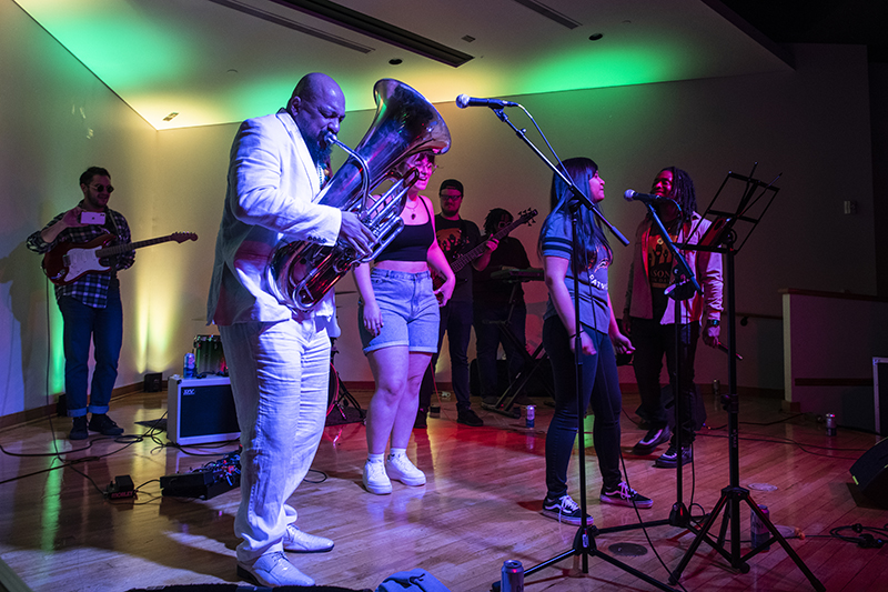 Dox Nix wears a white suit and plays the tub on stage with members of the Green Machine