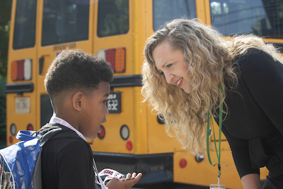 woman and boy by a school bus