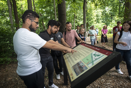 students read sign in wooded area