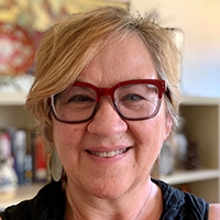 A smiling woman in eyeglasses looks at the camera.