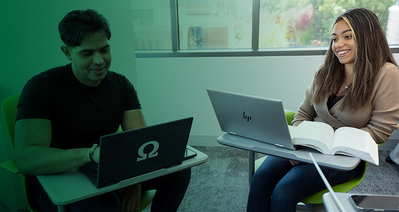 Two students sit together while using laptops in a Horizon Hall classroom