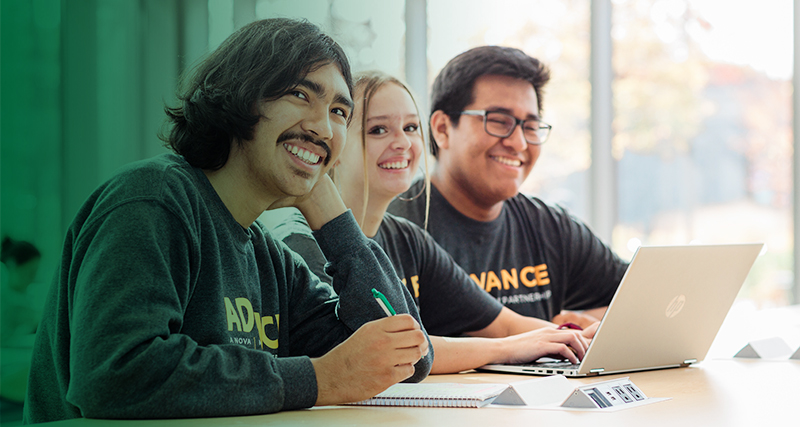 Students who are part of the ADVANCE program smile while working at a table together.