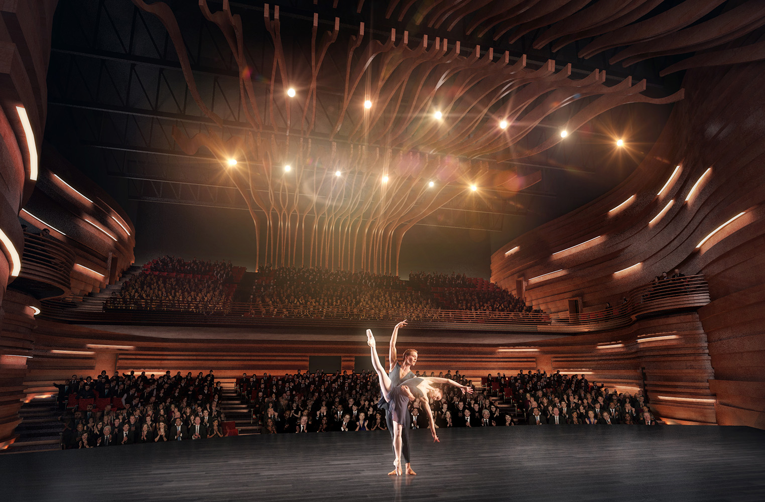Two ballet dancers on a stage, with the full audience visible behind them. The theater space has textured walls that look to be made of curved wood shapes.