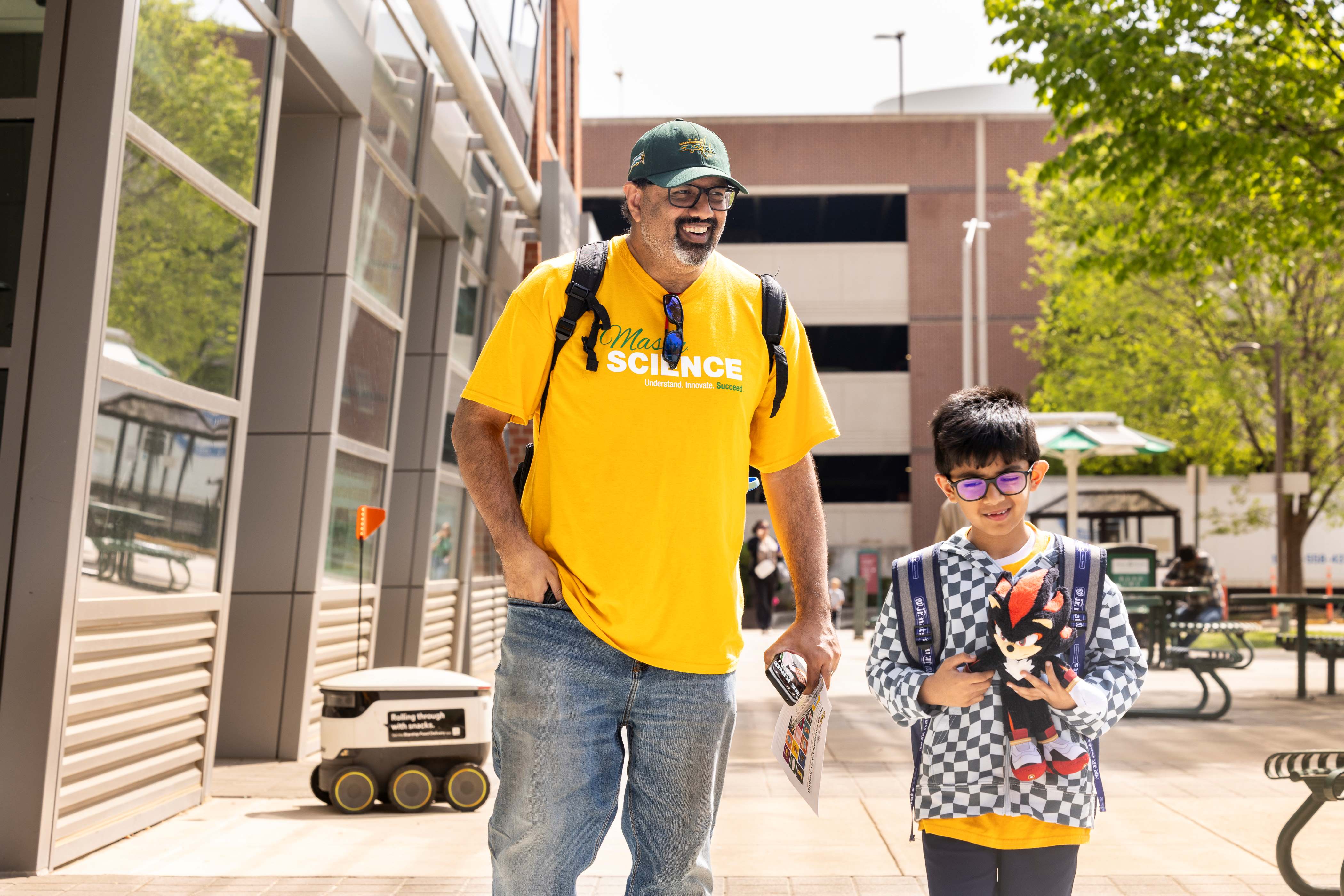An adult and a child walk together outside Merten Hall