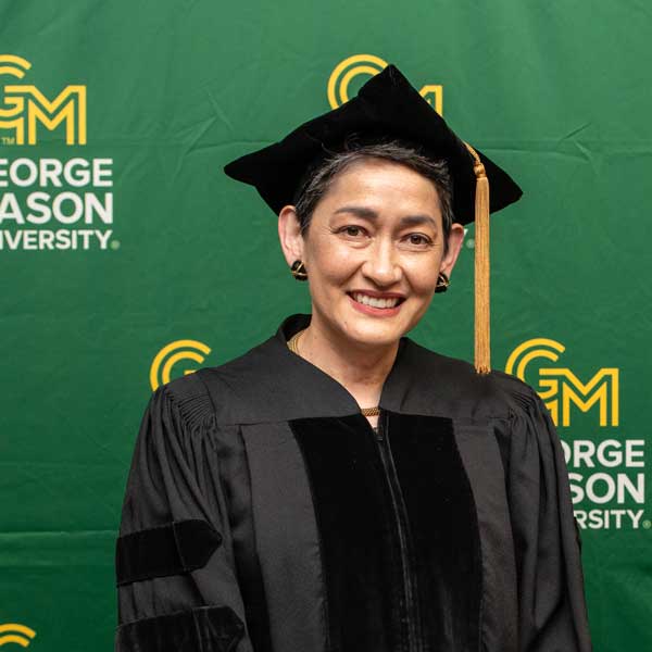 Martina Cheung wears academic regalia and smiles at the camera at George Mason University's Spring 2025 commencement proceedings