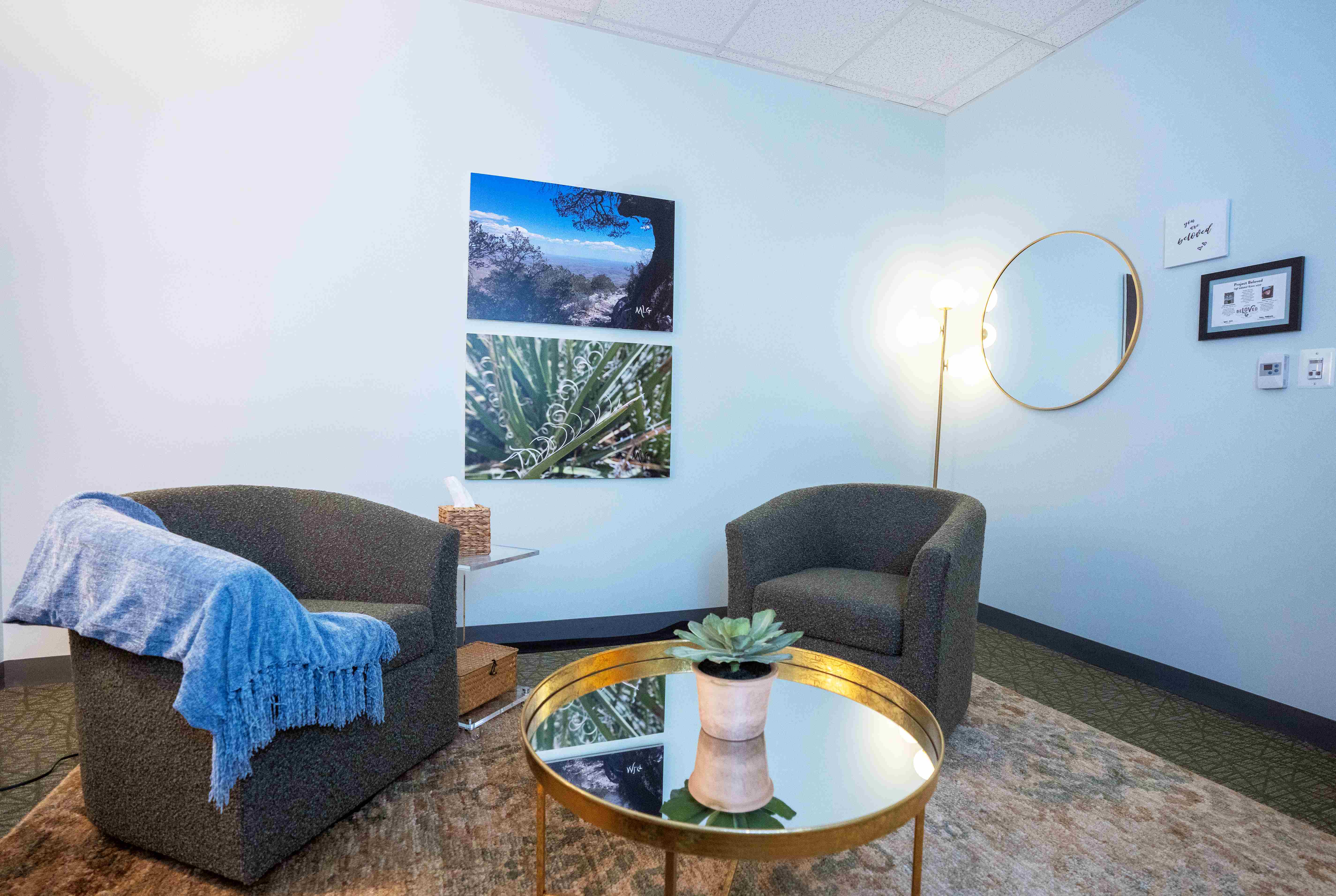 Soft interview room has comfortable chairs, soft lighting, and scenic landscape art on the wall