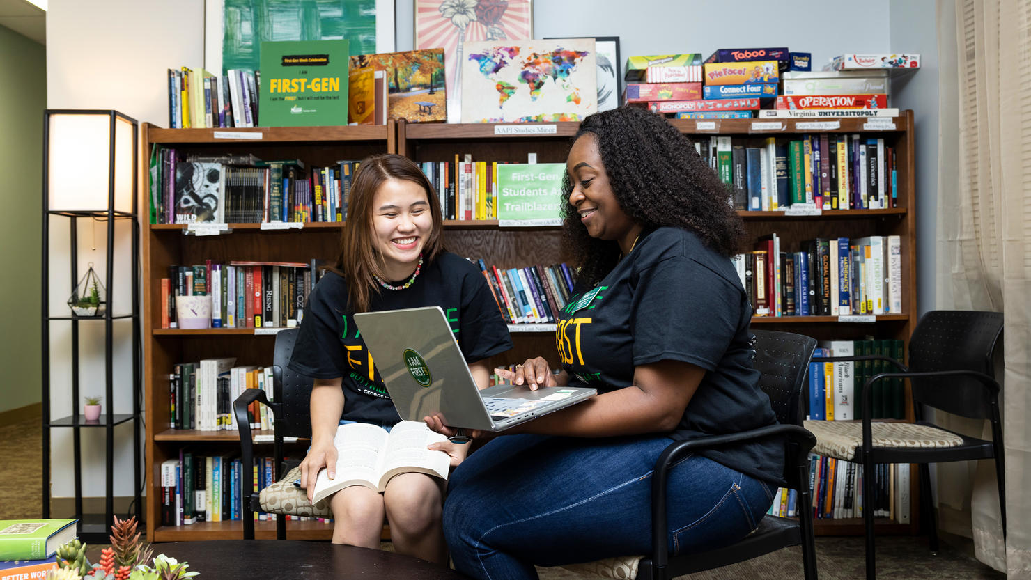 Two students sit in George Mason University's First-Gen+ Center examining a laptop.