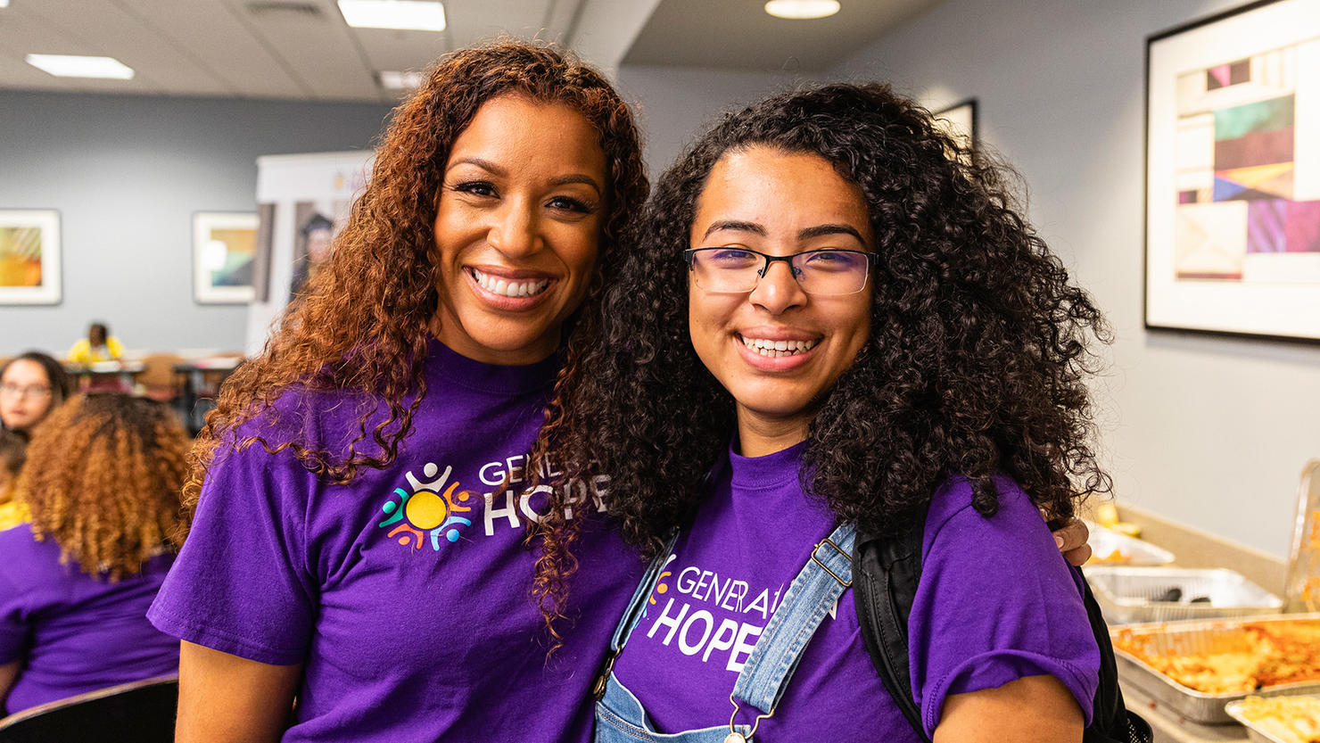 Nicole Lynn Lewis and Karen Escobar stand shoulder-to-shoulder and smile for the camera.