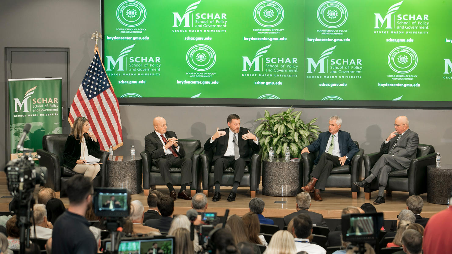 A panel of five people sitting on chairs on a stage.