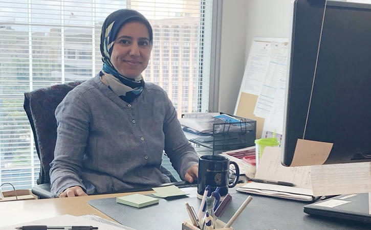 Tuqa Nusairat sitting at her desk and smiling at the camera.