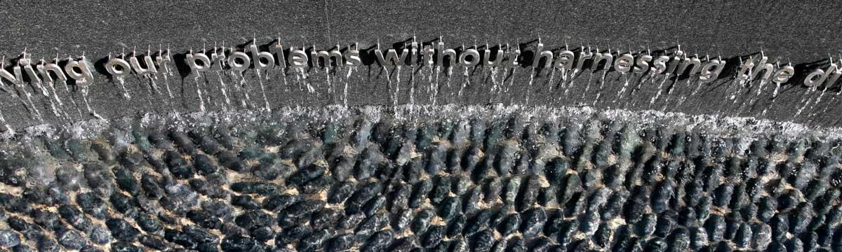 The words of Roger Wilkins are featured on a black granite monolith water feature on Wilkins Plaza at the center of George Mason University's Fairfax campus. Walter trickles over the letters into a reflecting pool lined with carefully arranged basalt stones in the memorial's reflecting pool.