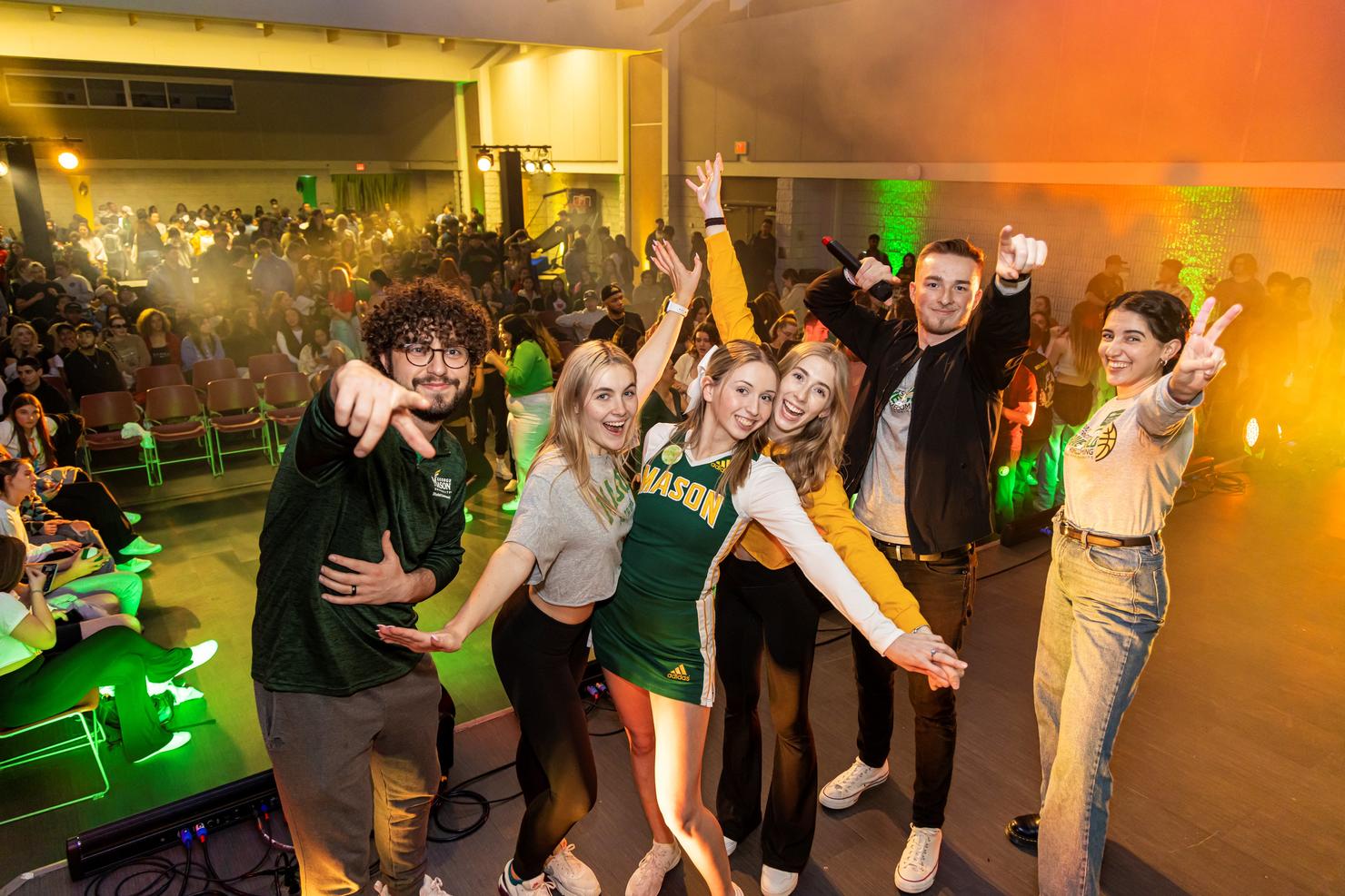 A group of students stand together on stage and pose during the Homecoming tip off party and lip sync battle