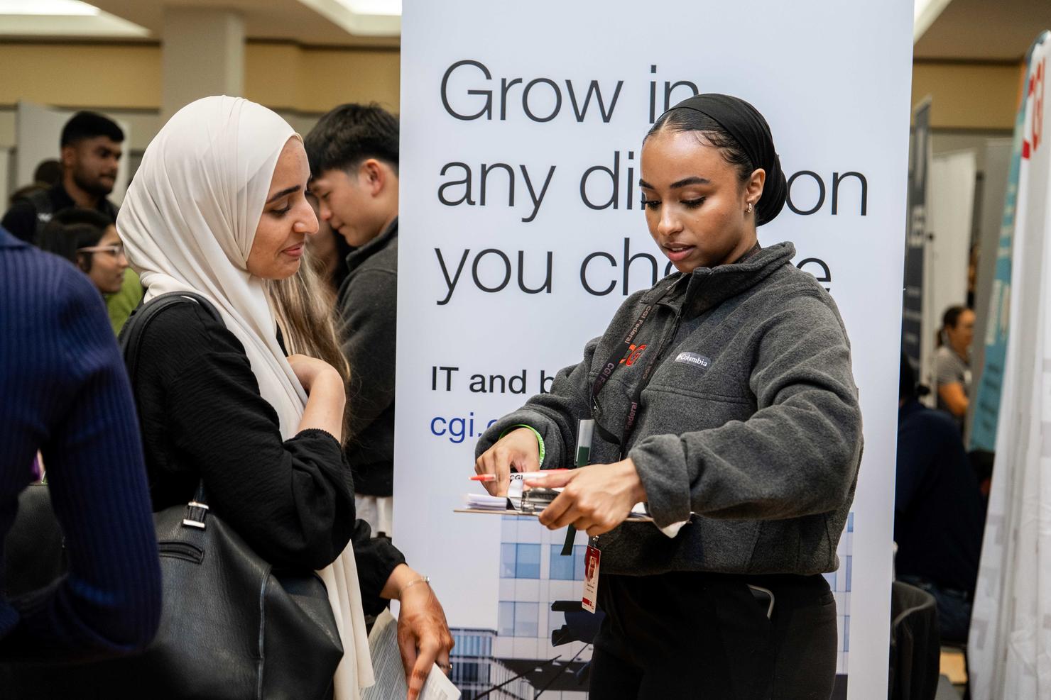 A student speaks with a prospective employer at the Career Fair. The recruiter is taking a document from their clipboard