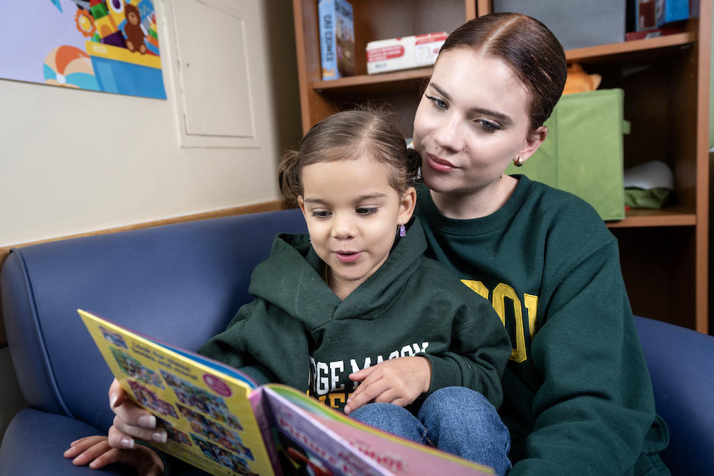 Portrait of Valeria Fernandez sitting and reading a book to her daughter