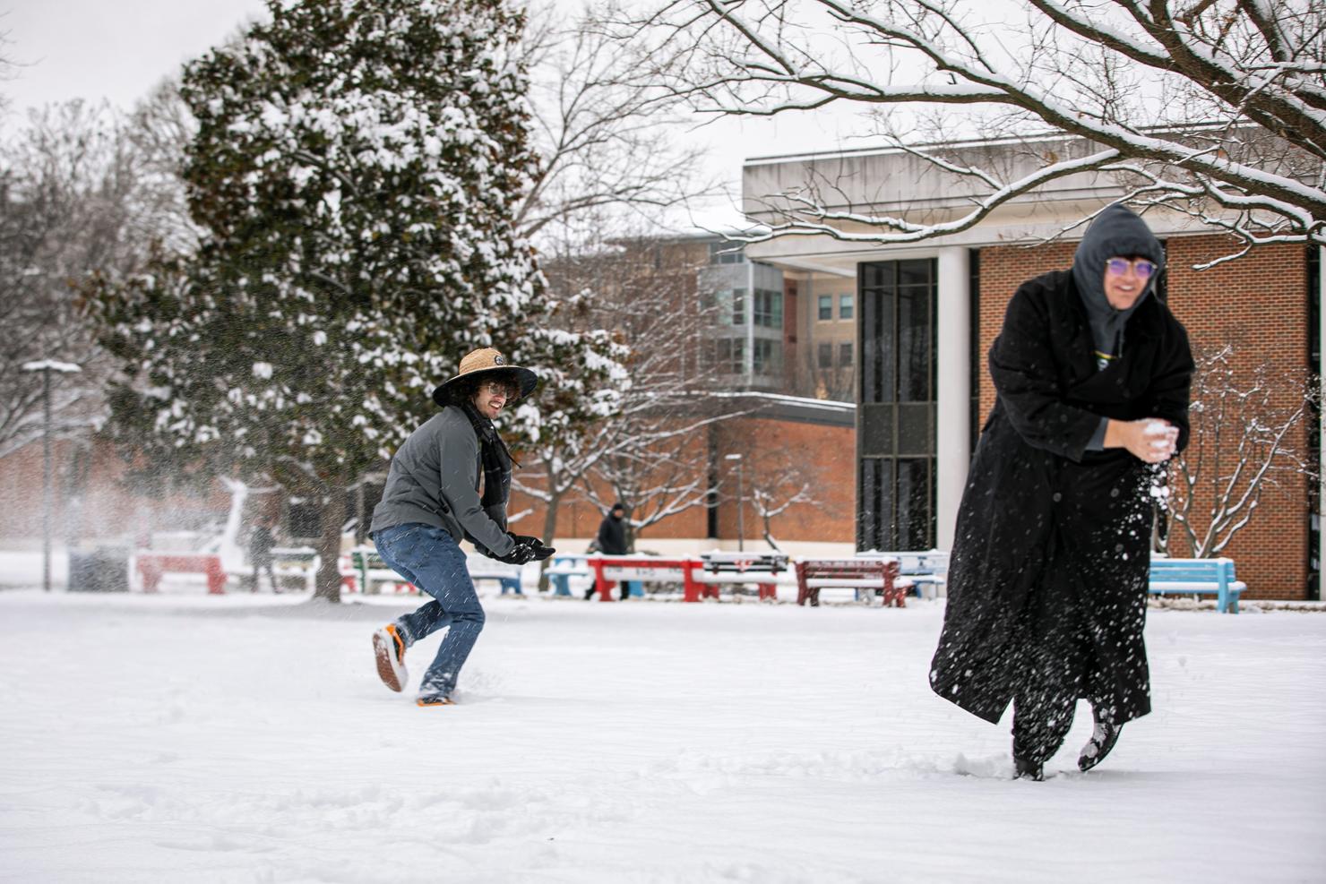 Two students get in a snowball fight on campus