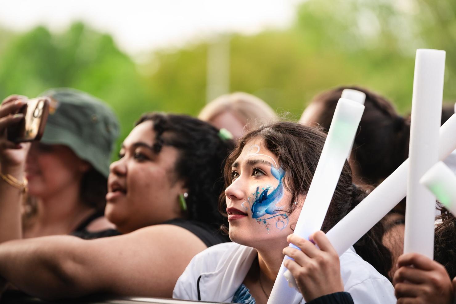 Student with dolphin face paint looks up at the stage at Mason Day