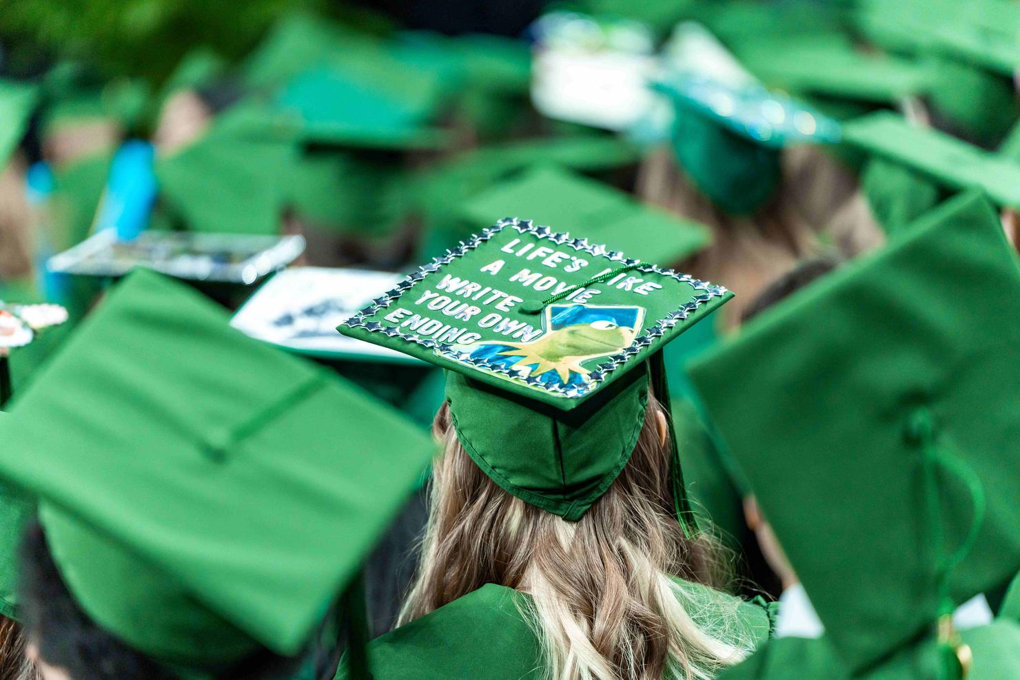 A decorated graduation cap has a picture of Kermit the Frog and says "Life's like a movie, write your own ending"