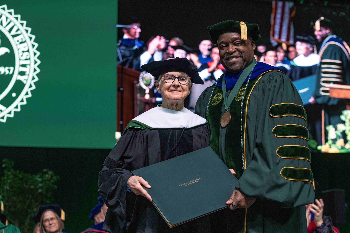 Maureen McCarthy Scalia and George Mason President Gregory Washington hold her honorary degree on stage at Commencement