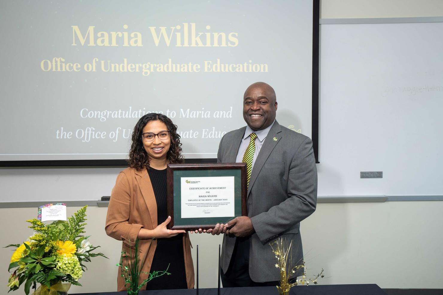 Employee of the Month Maria Wilkins holds her certificate with George Mason President Gregory Washington