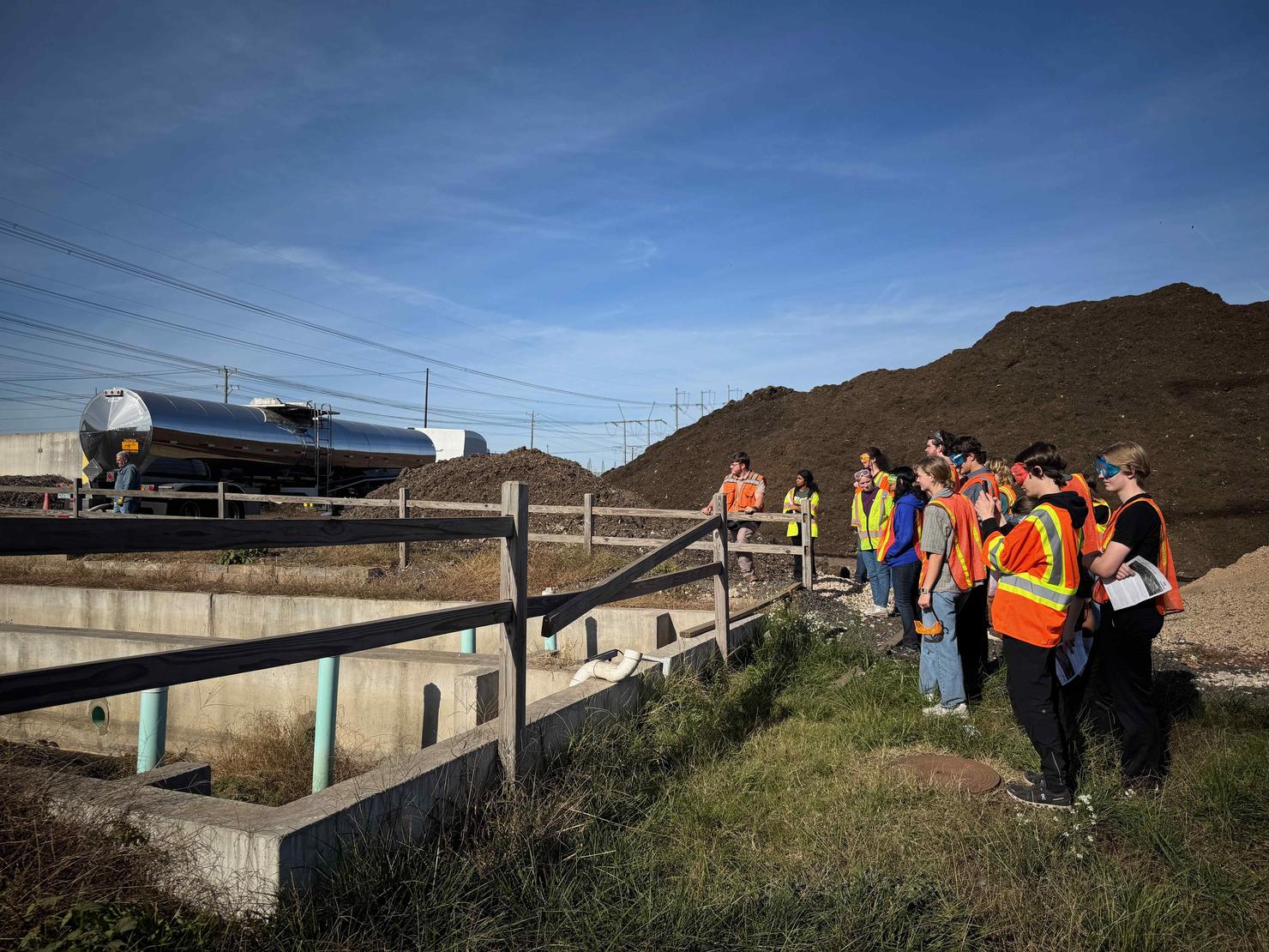 Student observe a tanker truck arriving with material at the composting facility
