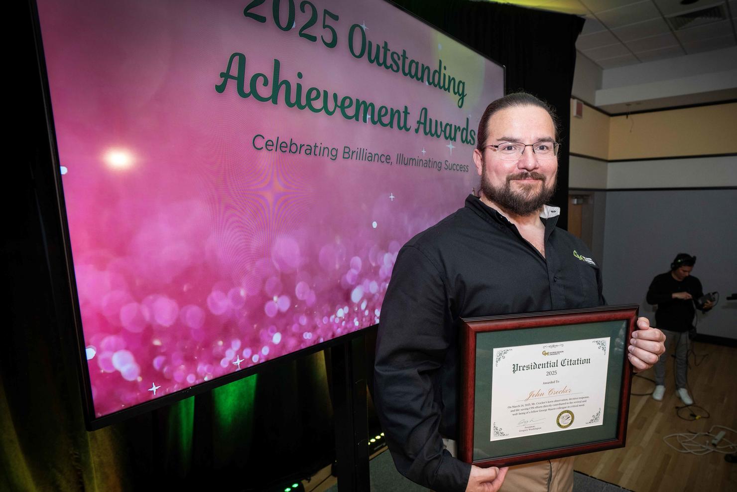 John Crocker holds his certificate on stage at the Outstanding Achievement Awards