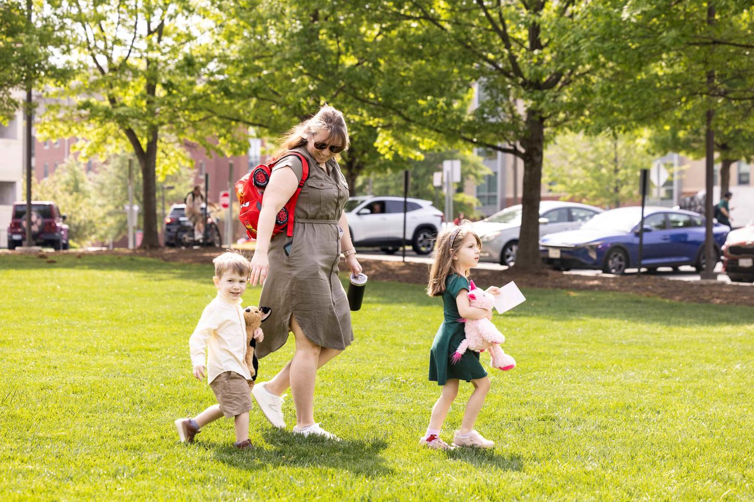 A George Mason staff member walks across Merten Lawn with her two young children