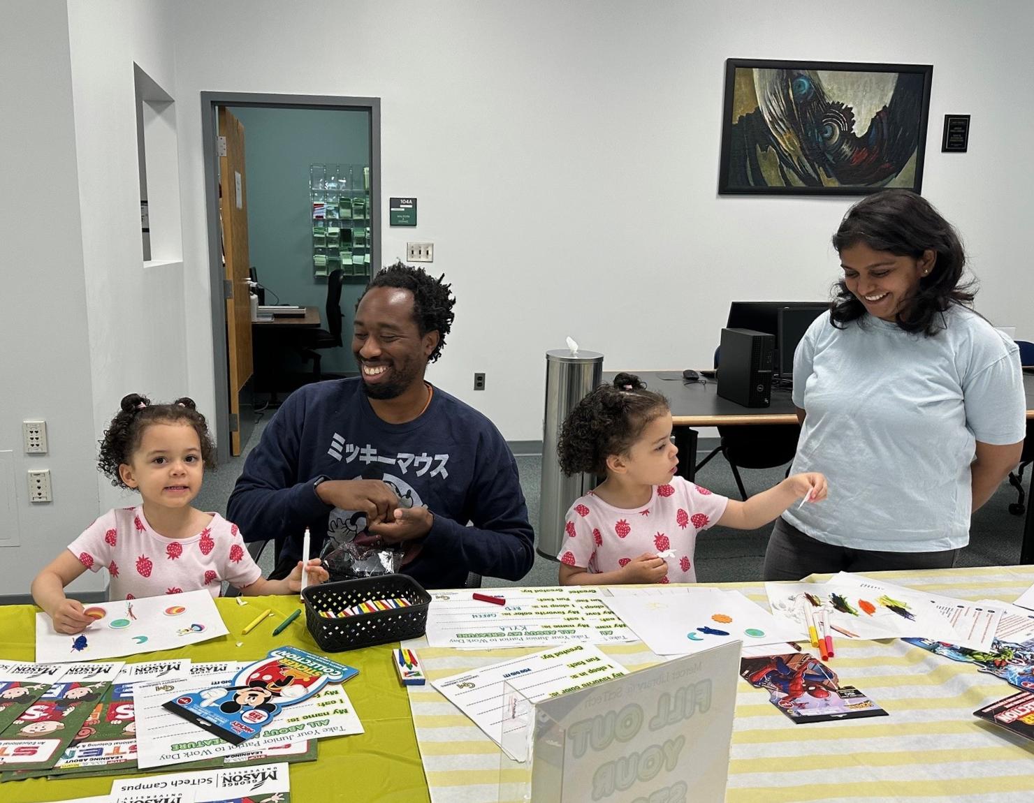 Two adults and two young girls do crafts together at the campus library