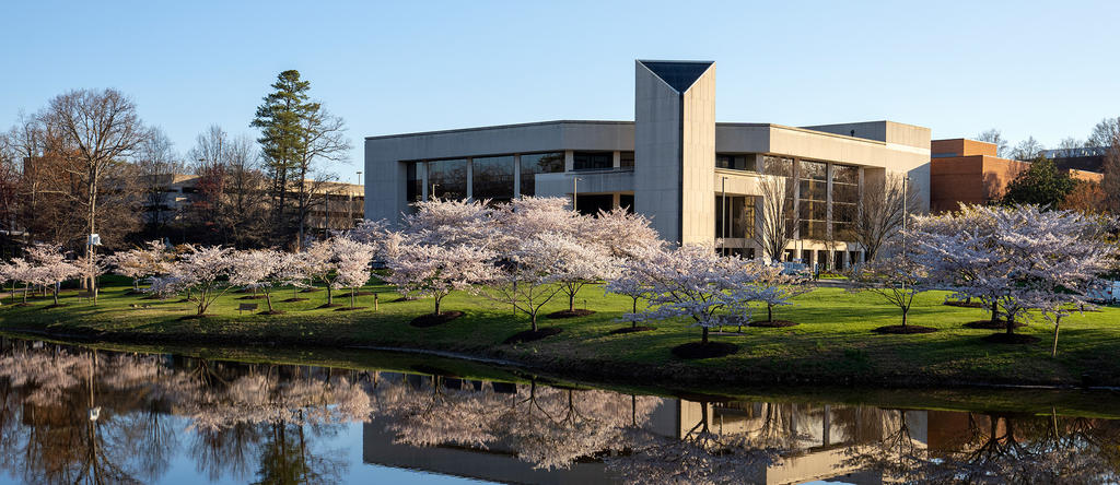 The Center for the Arts, as seen from across Mason Pond, with a reflection of the building in the water.