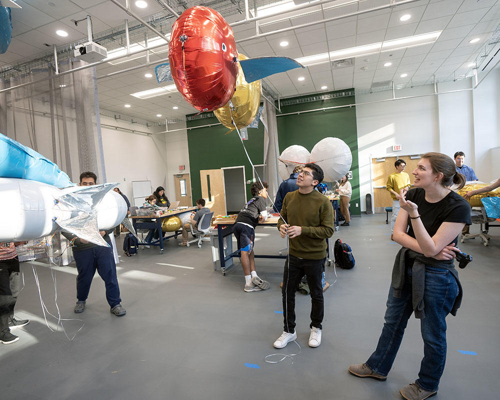 Students build and program blimps in a large well lit space in the MARC center