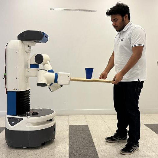 A student holding a tray with a cup on top of it is holding it out to a robot