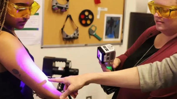 A special light held over a Black woman's arm to show intimate partner violence detection on multiple skin colors