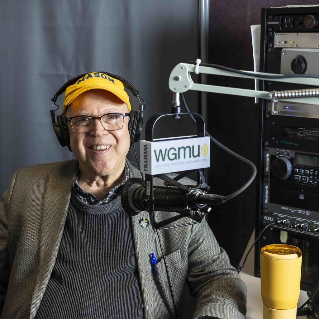Headshot of Rick Davis wearing a headset and leaning into a microphone for the recording of Access to Excellence podcast