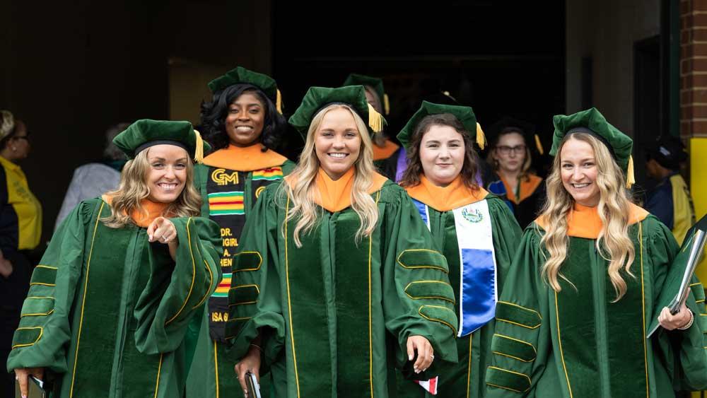 Celebratory doctoral graduates exit the arena with their degrees in hand. 
