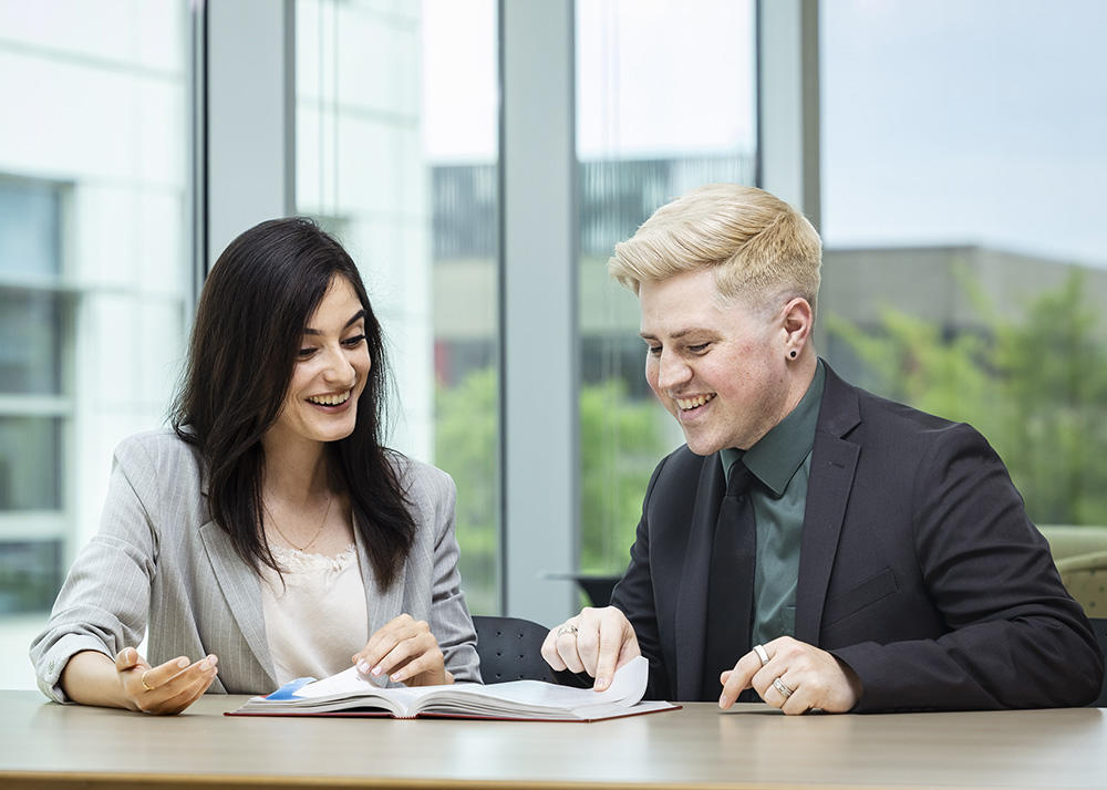 Two students confering at a desk