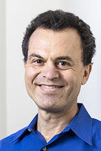 Giorgio Ascoli is wearing a blue button up shirt