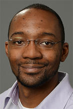 Richard Craig wears rimless glasses and a button down shirt