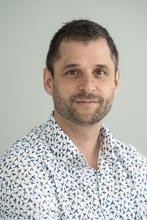 Remi Veneziano is wearing a patterned collared shirt