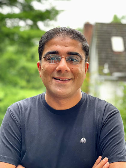 Parth Pathak standing outside in front of trees and a house, smiling at the camera.