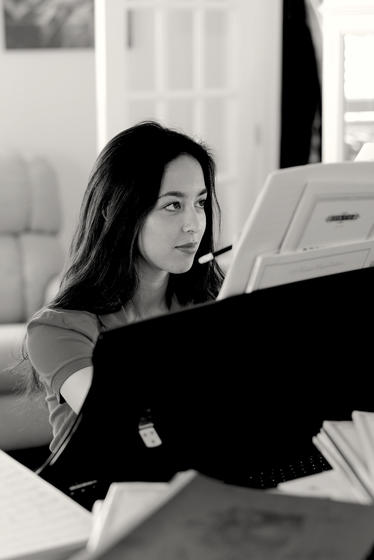 A black and white image of Catherine "Kitty" Fields, seated at her piano while she composes.
