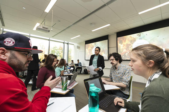 students in class listen to speaker at the front of the room