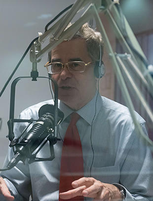 Mark J. Rozell talks to a microphone in a recording studio. His hands are mid motion as he explains a concept.