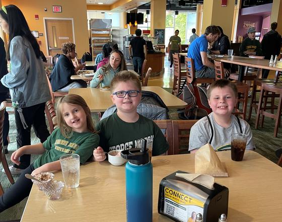 Three children sit at a table for lunch in Southside dining hall.