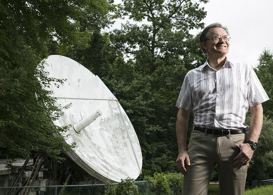 In this photo, a man, Peter Pachowicz stands next to a satalitte dish outside