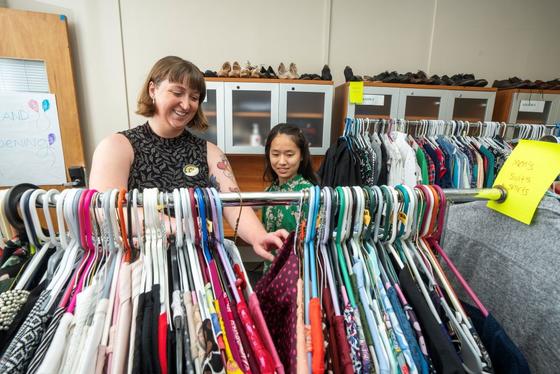 Students look through hangers of clothes in the clothing closet