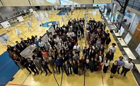 Governor's School students gather in a gymnasium with their research posters for the research symposium