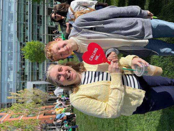 An adult and child pose together and smile in front of Merten Hall at the Take Your Junior Patriot to Work event