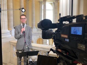 Nathan Crawford holds a microphone and is being filmed on camera.