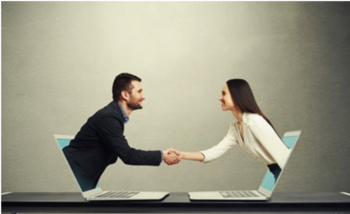 Two laptops facing each other with a man emerging from one screen and a woman emerging from the other screen, both wearing professional attire and shaking hands.